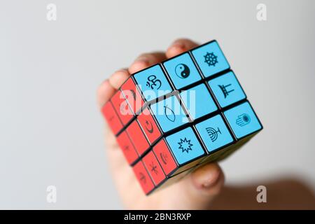 Femme avec un cube de Rubik avec des symboles religieux. Concept de dialogue interreligieux et interreligieux. Banque D'Images