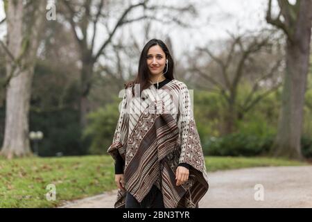 Femme indienne attrayante posant dans le parc regardant la caméra vêtue de poncho. Banque D'Images