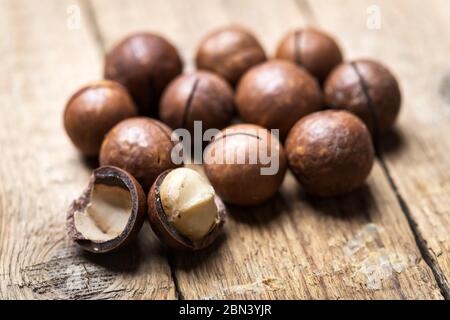 Noix de macadamia biologiques séchées sur une table en bois. Prise de vue macro studio. Fond noir en béton Banque D'Images