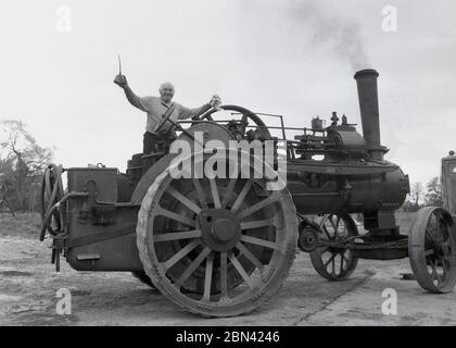 1980s, succès!... Un homme debout sur le dessus d'un grand tracteur à vapeur tenant un bidon d'huile et des chiffons, célébrant qu'il l'a fait courir, Angleterre. ROYAUME-UNI. Le tracteur à vapeur a été inventé à la fin des années 1880 par le fermier californien Daniel Best pour remplacer les chevaux de trait dans les champs, mais en raison de leur poids ne pouvait être utilisé que sur des champs secs. Étant si lourds qu'ils étaient aloso diffcultes à transporter. Banque D'Images