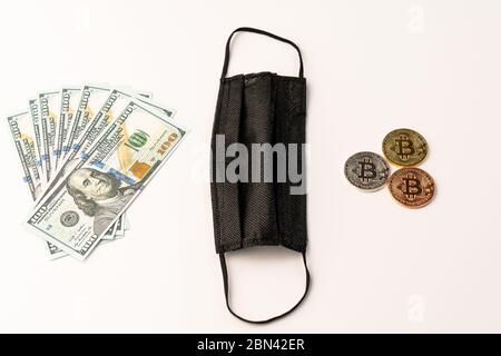 Masque médical noir sur fond blanc pièces de monnaie en bitcoin d'or et dollars américains gros plan Banque D'Images