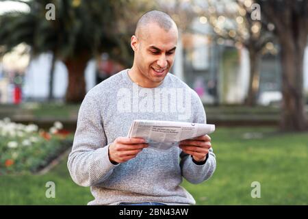 jeune homme lisant un journal Banque D'Images