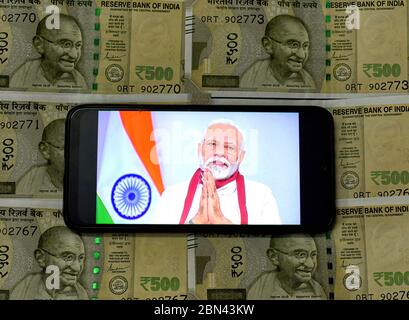 Kolkata, Bengale occidental, Inde. 12 mai 2020. Dans cette photo, le Premier ministre indien Narendra Modi a parlé à la Nation de la crise de Covid19 sur un smartphone avec un fond de la Note sur la monnaie indienne. Le Premier ministre, Narendra Modi a annoncé un plan économique spécial d'une valeur de RS 20 crate lakh INR/USD 300 milliards pour aider la nation à lutter contre la pandémie Covid-19. Crédit : Avishek Das/SOPA Images/ZUMA Wire/Alay Live News Banque D'Images