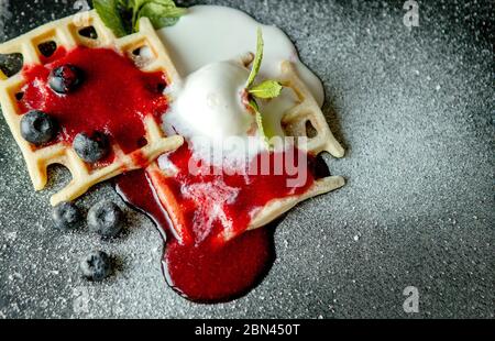 Gaufres belges classiques maison fraîches, parées de glace, de bleuets frais et de menthe, vue de dessus. Gaufres savoureuses. Concept petit déjeuner Banque D'Images