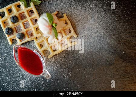 Gaufres belges classiques maison fraîches, parées de glace, de bleuets frais et de menthe, vue de dessus. Gaufres savoureuses. Concept petit déjeuner Banque D'Images