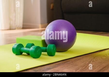 Bloc de mousse coloré, haltères et outils de boule en caoutchouc équipement sur tapis jaune pour l'entraînement à domicile, exercices de sport pendant l'isolement du virus pandémique Banque D'Images