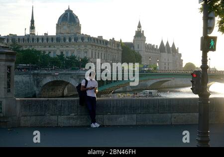 Un homme regardant son téléphone portable avec pont d'Arcole au-dessus de la Seine, la gréffe du Tribunal de Commerce de Paris et la conciergerie en arrière-plan.Paris.France Banque D'Images