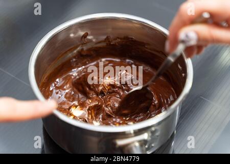 Femme qui fait fondre le chocolat dans une casserole et le mélanger avec du beurre Banque D'Images