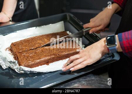 Femme qui coupe un gâteau au brownie fraîchement cuit en deux Banque D'Images