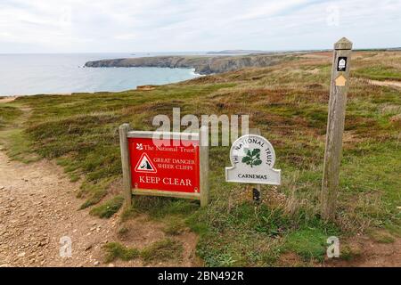 Un signe omega National Trust et un signe d'avertissement de danger - falaises abruptes à Carnepas, Cornwall, sud-ouest de l'Angleterre, Royaume-Uni PHOTO PRISE DE LA VOIE PUBLIQUE Banque D'Images