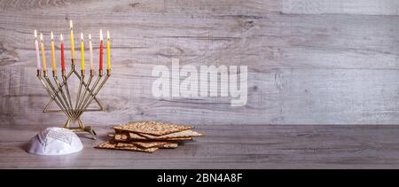 Symboles traditionnels de la célébration de Hanoukkah, de la menorah, du Matzoh et du kippah. Vue latérale. Bannière. Fond en bois clair Banque D'Images