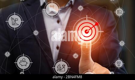 Atteindre les objectifs. Jeune homme d'affaires en appuyant sur cible et bouton fléché sur écran transparent, collage avec icônes de succès Banque D'Images