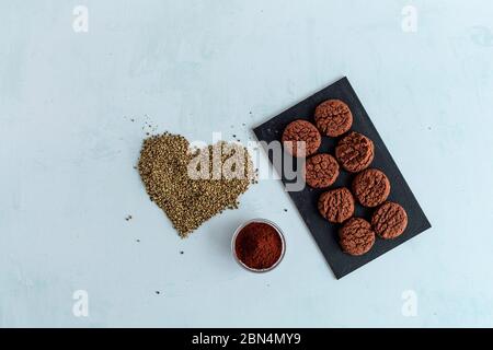 Biscuits au cannabis CBD, cacao et graines de chanvre en forme de coeur sur fond clair. Marijuana médicinale dans les aliments. Banque D'Images