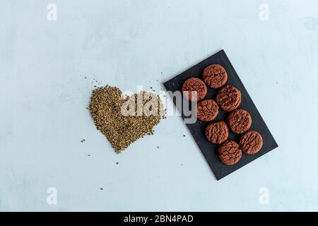 Biscuits au cannabis CBD, cacao et graines de chanvre en forme de coeur sur fond clair. Marijuana médicinale dans les aliments. Banque D'Images