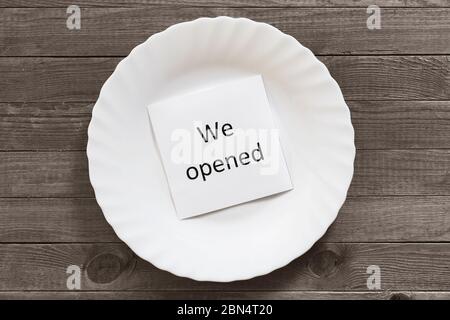 Note avec texte dans une plaque blanche sur une table en bois. Concept d'ouverture d'une entreprise de restauration en raison de mesures restrictives en relation avec le Covid-1 Banque D'Images