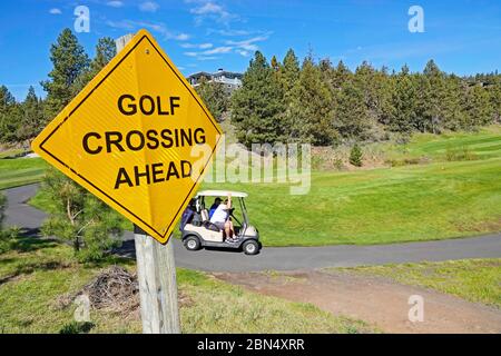 Les golfeurs qui utilisent une voiturette de golf à batterie vont de trou en trou sur un parcours de golf à Bend, Oregon. Banque D'Images