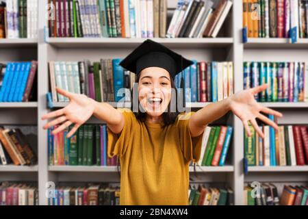 Jeune fille diplômée devant une bibliothèque. Concept de préparation et de détermination Banque D'Images