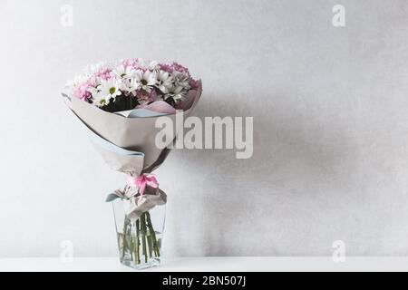 Bouquet de chrysanthèmes blancs et roses dans un vase en verre sur une table Banque D'Images