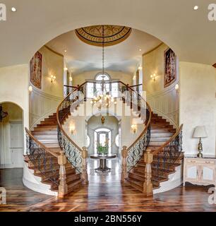 Le grand escalier avec marches d'escaliers en noyer, poteaux de newell et banisetrs dans une maison de construction de crème anglaise haut de gamme. Banque D'Images