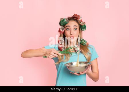 Délicieux concept de cuisson maison. Une fille en curlers prépare de la pâte dans un bol avec un fouet Banque D'Images