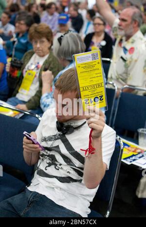 Houston, Texas, États-Unis, 9 juin 2012: Un jeune homme participant à la convention démocratique d'État du Texas regarde son téléphone cellulaire pendant qu'il tient sa carte de délégué officiel pendant une réunion d'affaires de convention. © Marjorie Kamys Cotera/Daemmrich Photographie Banque D'Images