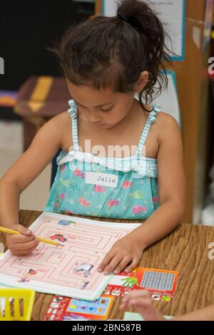 Austin Texas Etats-Unis, 17 mai 2012: Une étudiante de maternelle suit un labyrinthe à son bureau de salle de classe pendant une leçon sur l'argent et les nombres dans une école publique élémentaire du Texas salle de classe © Marjorie Kamys Cotera/Daemmrich Photographie Banque D'Images