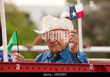 Austin Texas USA, mars 2012 : un homme hispanique âgé fait la vague d'un petit drapeau texan alors qu'il se déplace sur un flotteur dans un défilé du centre-ville célébrant le dévoilement du monument Tejano sur le terrain du Capitole. Le monument rend hommage aux contributions de Tejanos, les colons hispanophones qui ont apporté la culture du cow-boy à l'État. ©Marjorie Kamys Cotera/Daemmrich Photographie Banque D'Images