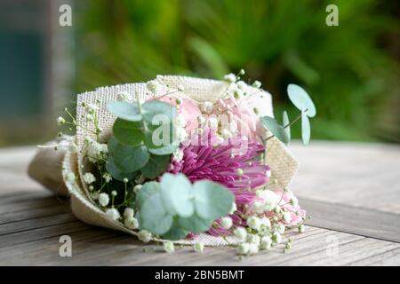 Le bouquet de fleurs à la main se compose de chrysanthème, de roses et de feuilles vertes. Sur la table. Banque D'Images