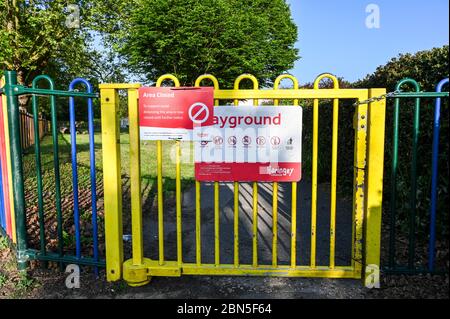 La porte verrouillée d'un terrain de jeu ou d'un parc de jeux avec un avis indiquant qu'il est fermé en raison de la pandémie du coronavirus. Banque D'Images