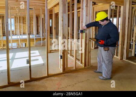 Inspecteur homme inspecte les systèmes électriques de maison électricien tenant tablette PC une maison en construction Banque D'Images