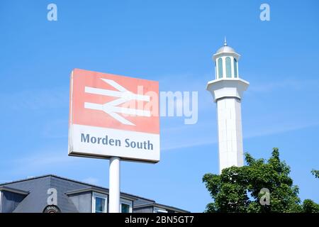 Panneau National Rail devant la station de métro Morden South avec un minaret de la mosquée Baitul Futah visible à droite. Banque D'Images