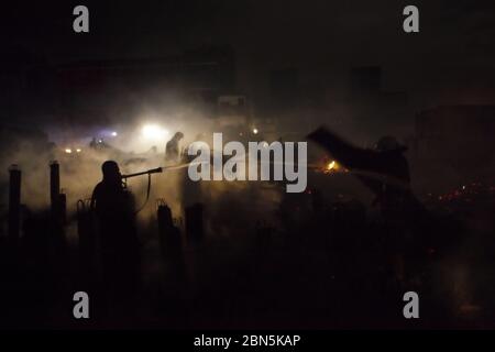 Les pompiers de Jakarta travaillent entre les débris après une bataille dans un quartier dense les membres de la brigade des pompiers de Jakarta refroidissent la zone, après qu'un accident d'incendie se propage et brûle des centaines de maisons dans un quartier dense à Penjaringan, dans le nord de Jakarta, Jakarta, Indonésie. Image d'archivage. 28 février 2011. Photo: Reynold Sumayku Banque D'Images