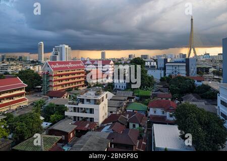 Dans la vieille ville de Bangkok, en Thaïlande, au-dessus d'un coucher de soleil orange-doré, la mousson sombre survole les nuages; à gauche: Wat Sam Phraya; à droite: Rama VIII Pont Banque D'Images