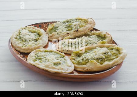 Sopes mexicains au fromage râpé et à la salsa verte, cuisine mexicaine épicée au mexique Banque D'Images