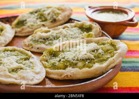 Sopes mexicains au fromage râpé et à la salsa verte, cuisine mexicaine épicée au mexique Banque D'Images
