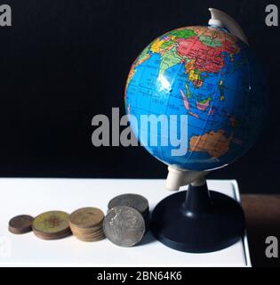 Pile de pièces indiennes sur fond noir avec carte du globe. Métaphore des affaires, investissement financier et concept économique. Pile de pièces indiennes au bar Banque D'Images