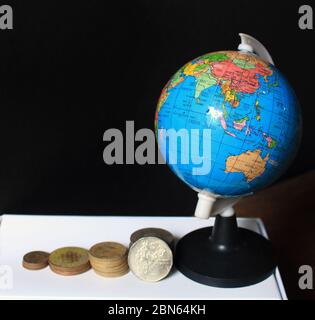 Pile de pièces indiennes sur fond noir avec carte du globe. Métaphore des affaires, investissement financier et concept économique. Pile de pièces indiennes au bar Banque D'Images