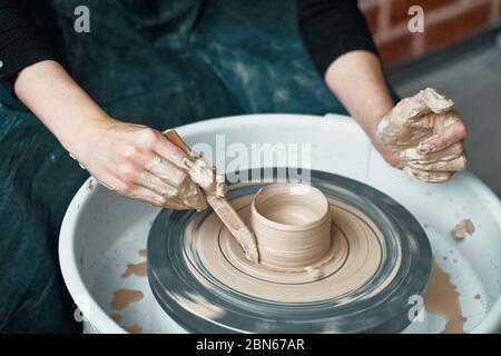 Femme faisant de la poterie en céramique sur la roue, les mains près, la création de céramique Banque D'Images