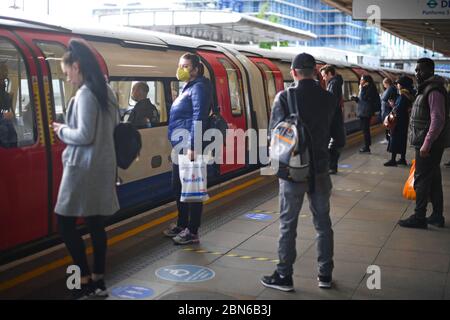 Les passagers portent un masque facial et se tiennent à l'écart sur une plate-forme à la station de métro Canning Town de Londres, après l'annonce des plans pour mettre le pays hors de l'isolement. Banque D'Images