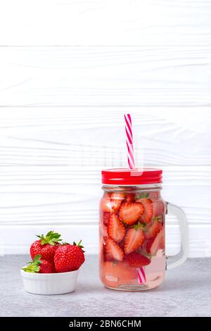 Eau, cocktail, limonade ou thé infusés à la fraise. Boisson fraîche glacée d'été avec fraise, citron et feuille de menthe sur fond de bois blanc. Plat Banque D'Images