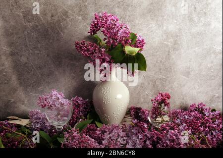 Bouquet de lilas violets dans un vase blanc placé au centre de la photo horizontale. Copier l'espace des deux côtés. Banque D'Images