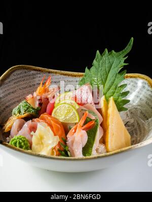 Salade Sahimi avec thon finement tranché, poisson roi et saumon avec ananas, citron, wasabi, feuilles de salade Banque D'Images