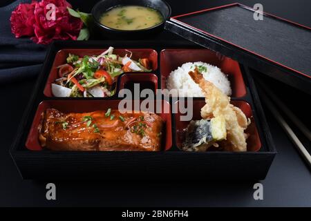 Portion de nourriture fraîche dans une boîte à Bento japonaise avec petits pains à sushis, salade et plat principal. Gros plan sur le riz et la viande friture Banque D'Images