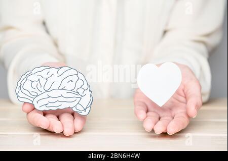 Les mains des femmes tenant le papier coupent le cerveau et l'âme. Conflit entre les émotions et la pensée rationnelle. Équilibre et équilibre entre l'esprit et le coeur concept Banque D'Images