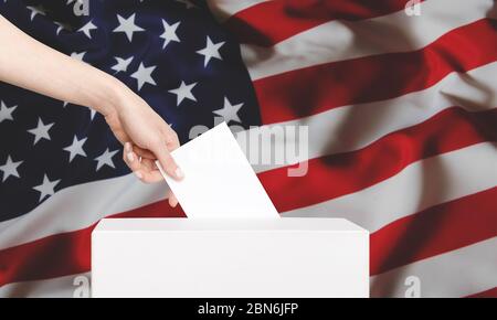 Une femme votant dans une boîte de vote sur le drapeau américain de fond. Concept de liberté démocratie avec espace de copie Banque D'Images