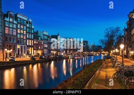 Canal d'Amsterdam avec des maisons de danse hollandaises typiques la nuit avec des reflets de lumières de la ville dans l'eau, Hollande, pays-Bas. Banque D'Images