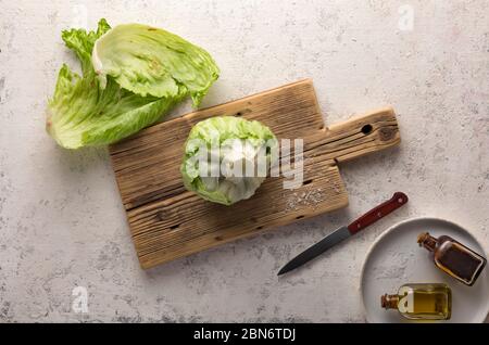 Salade iceberg sur planche à découper, fond en béton, vue de dessus Banque D'Images