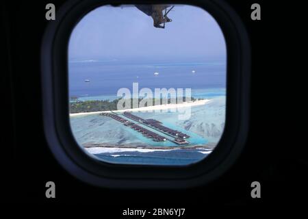 Vue aérienne à travers les fenêtres d'avion sur l'île tropicale des Maldives Banque D'Images