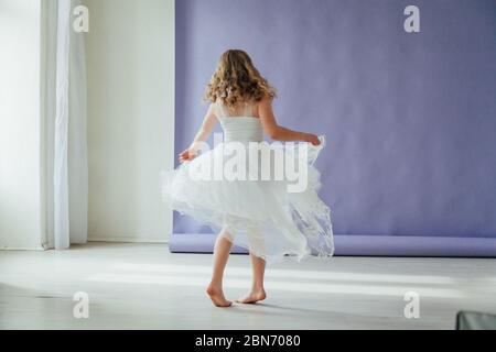 Belle petite fille en robe danse seule à la maison Banque D'Images