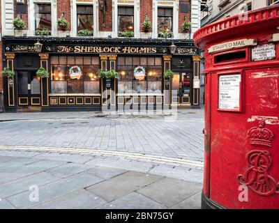 Scène de rue de Londres. Une ancienne boîte postale rouge devant un pub anglais traditionnel, le Sherlock Holmes, à Westminster. Décorations de Noël visibles. Banque D'Images